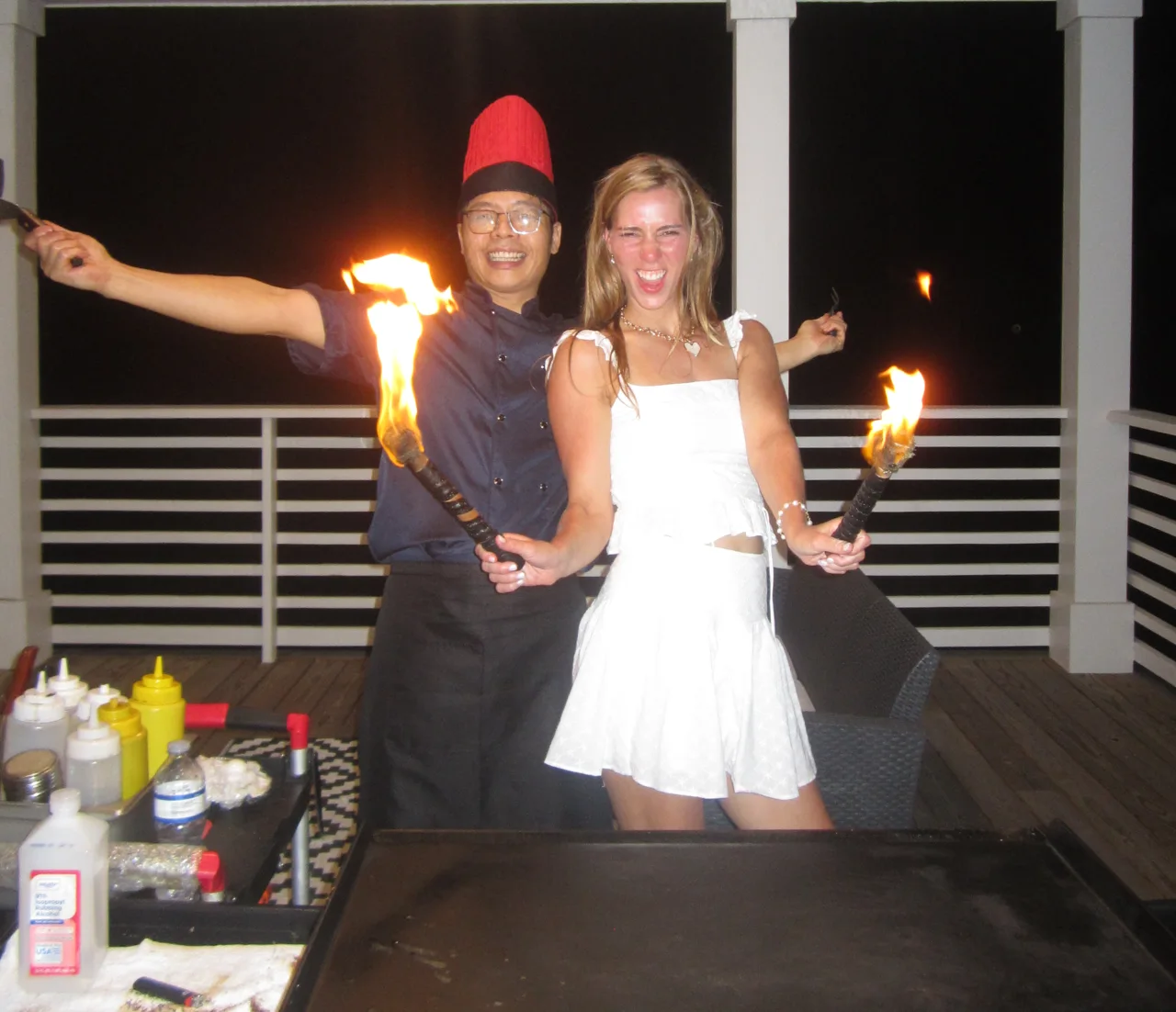 Hibachi chef and guest enjoying a fire show on an outdoor porch