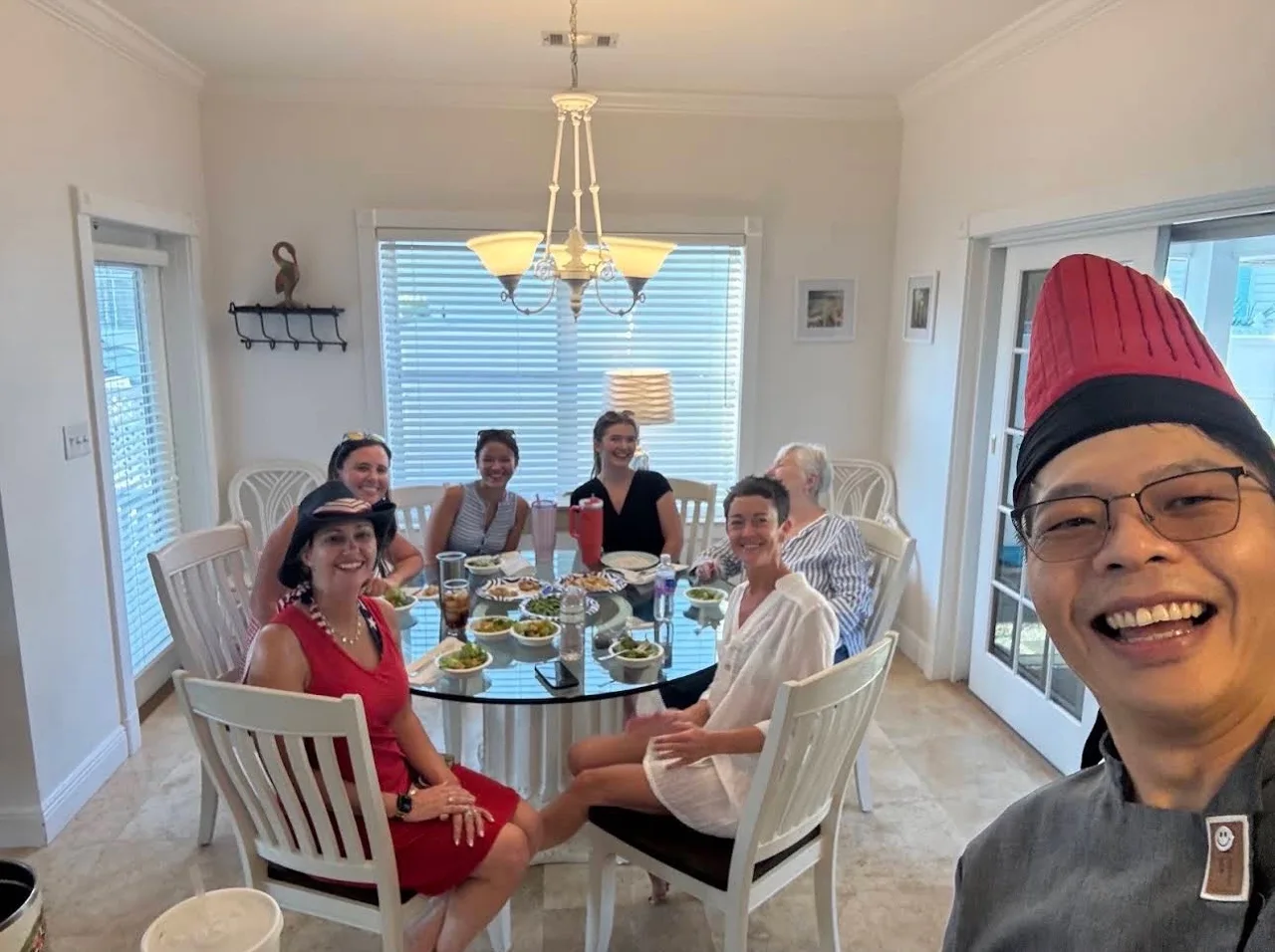 Chef and guests sharing a hibachi meal at a home dining table