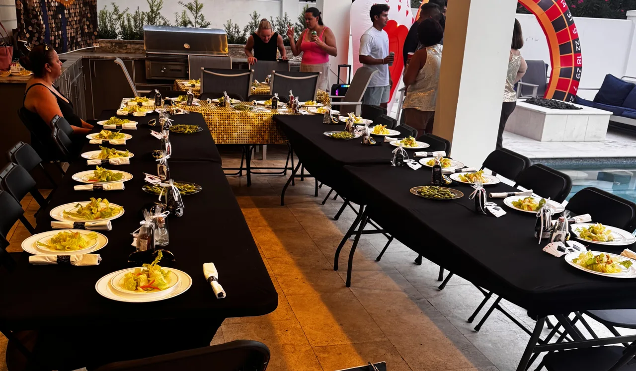 Tables, chairs and place settings arranged beside a home swimming pool